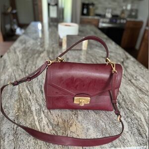 Michael Kors burgundy handbag with shoulder strap and satchel straps.